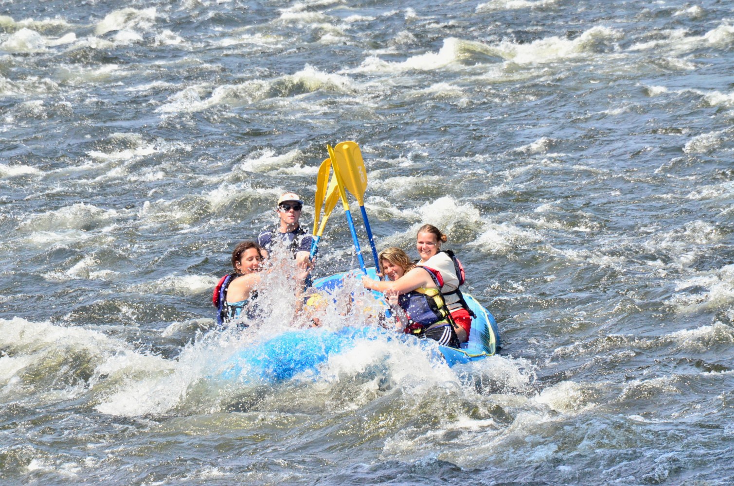 Group of people whitewater rafting on a river.